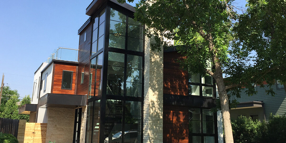 A real modern Denver home with a dramatic two-story wall of windows on a sunny day